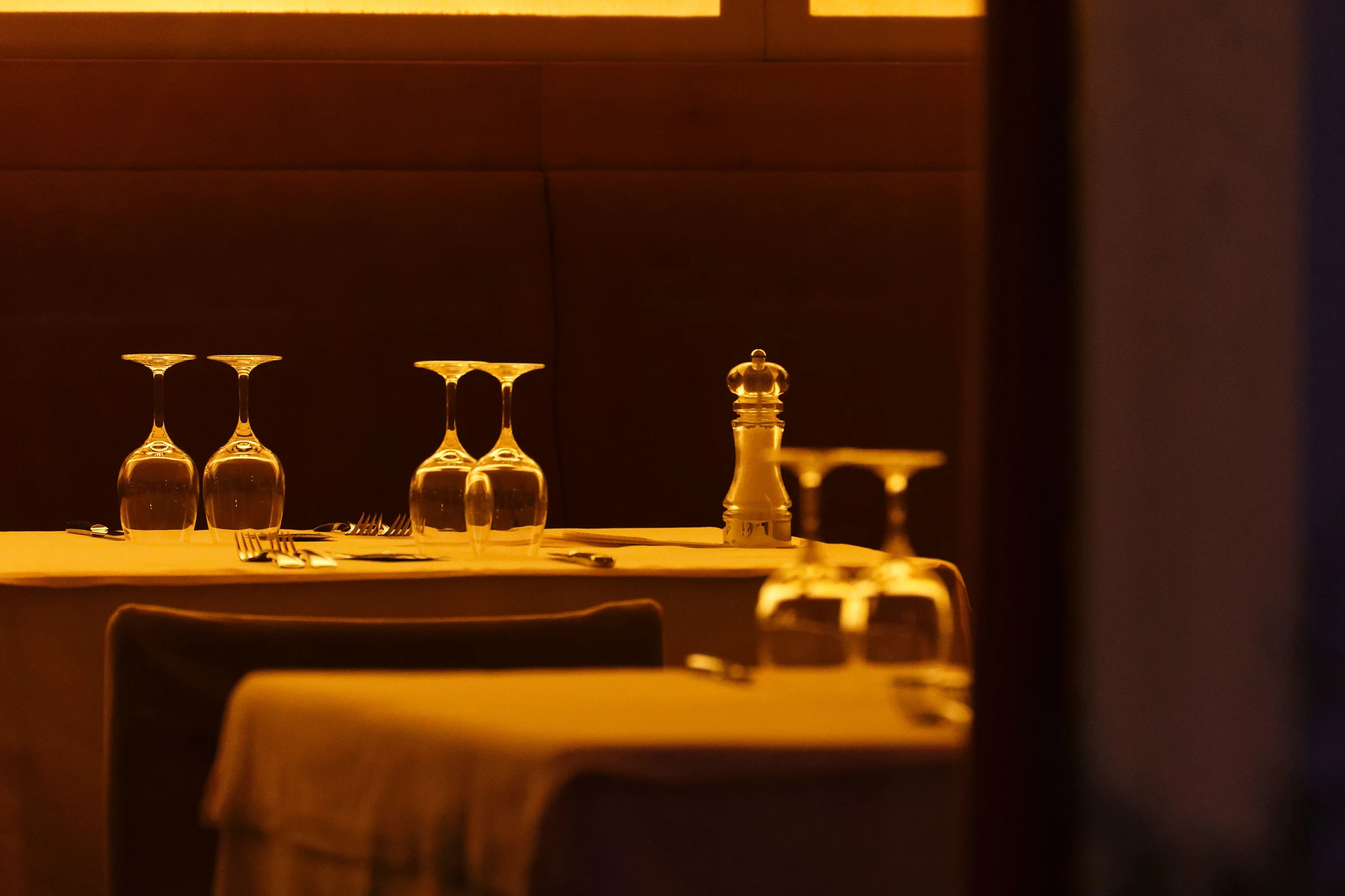 Cozy restaurant dining room with warm sunlight, set tables, and wine glasses
